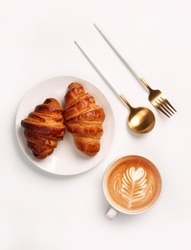 Morning breakfast setup. Croissant with coffee cup on white background.