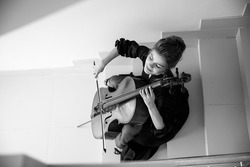 cellist sits on the stairs and plays the cello, enjoys playing music, top view, black and white image, suitable for a poster or poster