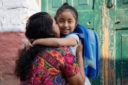 Hispanic Mayan mom hugging her little daughter ready for her first day of school-little girl with her mother ready to go to school- Back to school in Latin America