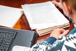 Woman author re-writing her manuscript after it has been proofread by an editor.