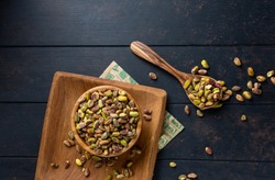 Raw peeled green pistachio nut in a wooden plate on a dark background. top view overhead view   copy space Close up view


