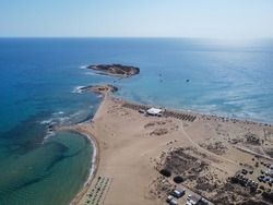Aerial drone view of the island and beach of Isola delle Correnti with and old lighthouse surrounded by clear turquoise sea water. Southernmost point in Sicily, Portopalo di Capo Passero, Italy.