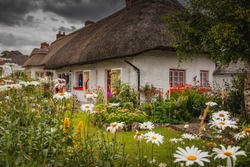 Adare, Ireland. Thatched cottage in the picturesque Village of Adare, Co. Limerick full of flowers in front garden. Ireland, Europe