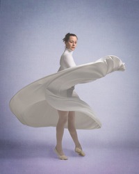 Dancer in a white dress twirls around as the skirt flutters with the movement