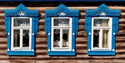Old wooden windows with carved architraves. Log facade of typical rural house of Nizhny Novgorod region, Russia. Architecture concept.