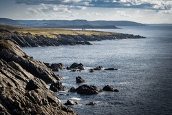 East Coast scene of rocky headlands with lone cabin overlooking the Atlantic Ocean at Cape Bonavista Newfoundland Canada.