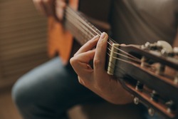 Man playing acoustic guitar, cover for online courses, learning at home