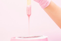 liquid wax for pink depilation drains from the stick. The concept of depilation, waxing, smooth skin without hair.