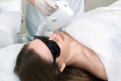 Laser hair removal of the mustache and chin of a young beautiful woman. Depilation on the face. Device for laser hair removal.