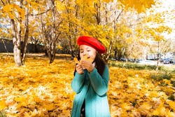 Portrait Cute child in red beret and green knitted coat against the background of yellow leaves the autumn forest. Autumn mood and concept.