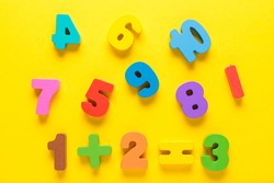 Wooden colored numbers on a yellow background. Mathematic topic. Back to school concept. Child education, learning mathematics and counting. Early childhood education. Elementary mathematics.