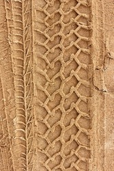 Tire prints on a wet yellow sandy road. Top view. Background for the design. Vertical photo.
