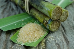 Sugar and Sugar cane on leaf and wooden background
