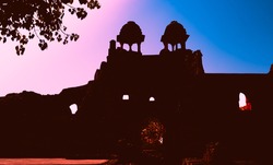 Silhouettes of an Old Fort in Delhi with blue and pink sky background. Famous historical travel destination in India known as Purana Qila or Quila. Abstract background and history concept.