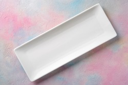 Empty white long rectangular plate on a colored background.
