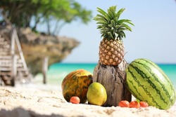 Ripe fruits laying on a beautiful abandoned beach of Zanzibar island with white sand clifs and ocean pineapple mango watermelon and papaya on a sunny day in summer holidays high quality resolution hd