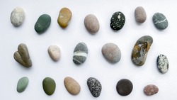 Collection of various sea pebble stones on white background.  Top view, flat lay.