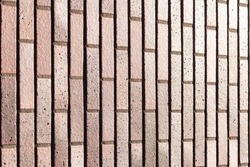 Dark brown redish bricks used in new modern architecture, the wall of an exteriror residential home. Chique stylish trend in darker stone tiles and bricks creating a luxury feeling in the sun