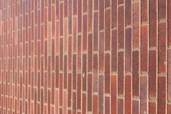 Dark brown redish bricks used in new modern architecture, the wall of an exterior residential home. Chique stylish trend in stone tiles and bricks creating a luxury feeling, horizontal selective focus