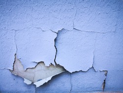 closeup of damaged weathered and paint pealing from blue painted wall
