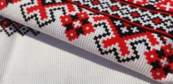 White towel with geometric, red and black patterns; machine sewing (diagonal fold, texture).
