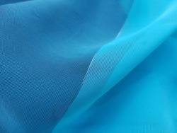 Wavy turquoise blue translucent fabric with a golden thread with diagonal fold (macro, texture).