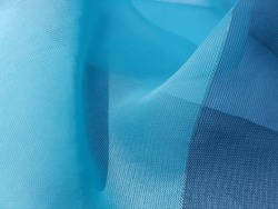 Wavy turquoise blue translucent fabric with a golden thread, in folds (macro, texture).
