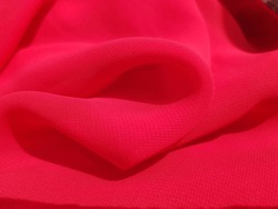 Wavy red chiffon fabric with a convex fold (macro, texture).