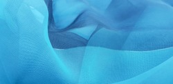 Wavy turquoise blue translucent fabric (chiffon) with a golden thread, in folds (macro, texture).
