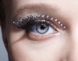 Closeup macro shot of human female eye with unusual makeup. Woman with rhinestones arrows on eyelid.