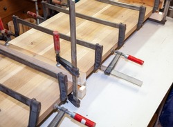 DIY. clamps to group timber. Oak Wooden kitchen counter top. Glued pieces of wood and carpentry clamp. Carpentry accessories in a wood workshop. Production of wood furniture. Furniture manufacture.