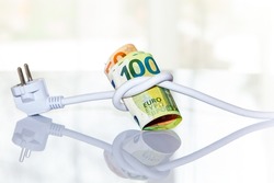 Roll of Euro banknotes tied up with an electrical plug. on light background. Concept of saving electricity at home. Electricity consumption costs and expensive energy concept. 
