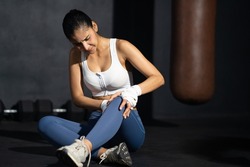 Young adult Asian women feeling painful from knee muscle injury after workout with weight lifting, cross training at fitness gym. Muscle injured from workout or exercise, weight training.