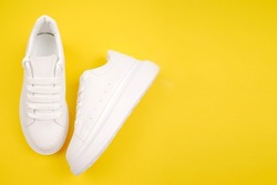 A pair of stylish women's leather shoes on a high platform with laces on a yellow background.Casual comfortable white shoes.Seasonal sales, discounts on shoes. Proper care for white skin.Copyspace