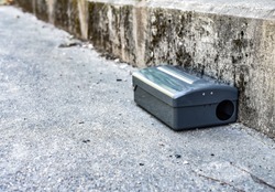 Black Metal external rodent rat bait station outside against a wall close up.  Pest Control.