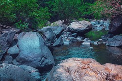Strong flood of water rocks below.Crystal clear water, huge stones with a beautiful vegetation around. At the end forming a strong current and later a calm lake with clean transparent in India