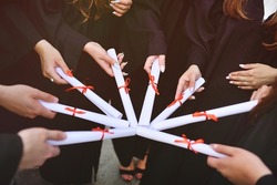 graduate students in black robes holding diplomas or certificates of graduation from a higher educational institution.