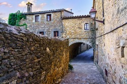 Nice alley with medieval houses and arched passageways under the buildings, Peratallada, Girona, Spain.