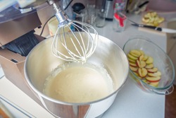 Planetary mixer with dough in a bowl. Process of cooking charlotte pie. Apple Pie dough and glass bakeware. delicious homemade grandma pie recipe. mixer metal whisk for stirring and whipping