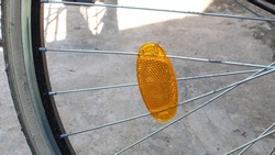 Fragment of bicycle wheel with plastic reflector orange color installed between the spokes