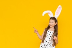 A beautiful girl in an Easter bunny costume points at the advertisement and smiles.