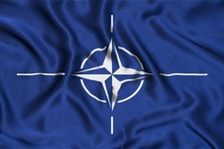 Flag of NATO on silk. Waving flag of NATO.  NATO flag as a background.