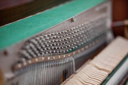 The inside of the piano is without a lid. Strings, hammers and other parts of a musical instrument are visible. Tuning and repair of a musical instrument
