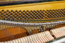 The inside of the piano is without a lid. Strings, hammers and other parts of a musical instrument are visible. Tuning and repair of a musical instrument