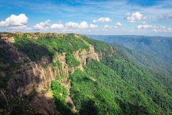 mountain range covered with green forests and bright blue sky at afternoon from flat angle image is taken at seven sister waterfall cherrapunji meghalaya india.