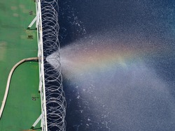rain bow on water spray from fire hose on a cargo ship which fitted with razor wire during passing piracy high risk area. 