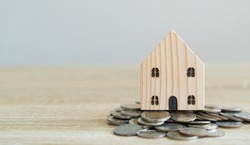 Money savings concepts. Wooden house models with coins in meaning about saving money to buy a house, refinancing, investment or financial on wooden table with blur background and copy space