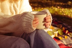 girl in a warm white sweater holds Cup of coffee. Autumn background, the concept of warmth and comfort