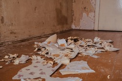 A pile of torn off wallpaper on a background of a concrete wall Repair removal of old wallpaper vintage paper pergament