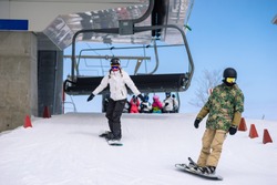 Snowboarders disembark from a chairlift